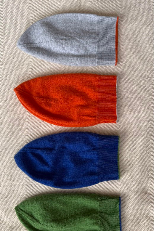 Four STABLE cashmere beanies in grey, orange, blue, and green, crafted by Irish makers with high-quality, soft textiles.