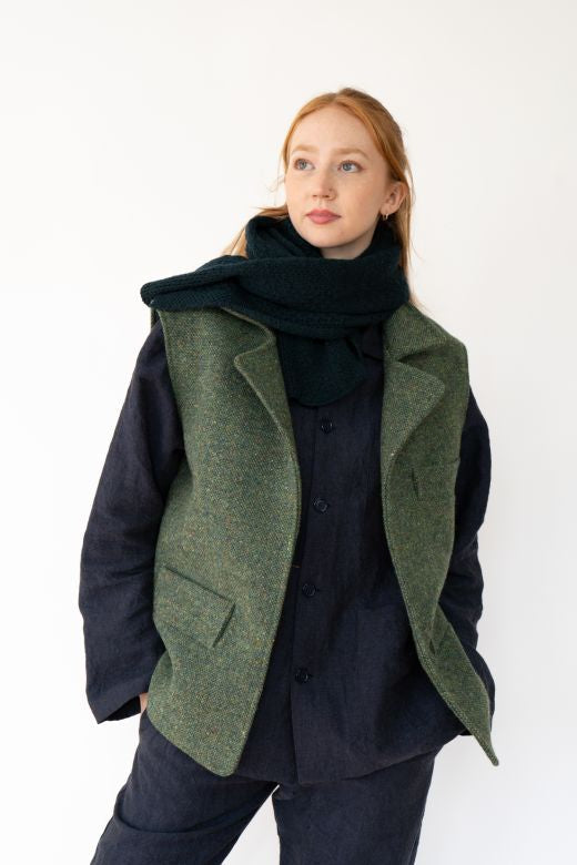Green Irish flecked tweed gilet featuring high-quality craftsmanship from Irish makers, worn over a dark linen shirt and scarf.