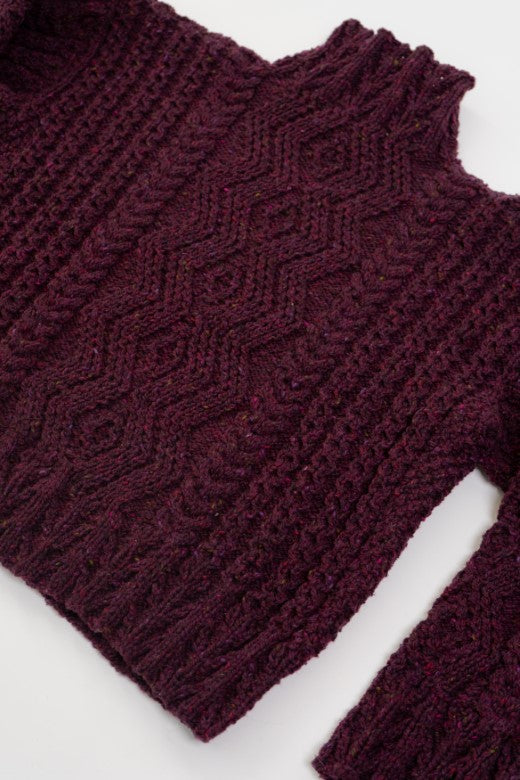 Deep purple handknit merino wool Aran jumper featuring traditional blackberry stitch, crafted by Irish artisans.