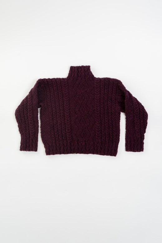 Deep plum handknit merino wool Aran box jumper with intricate blackberry stitch, crafted by Irish artisans.