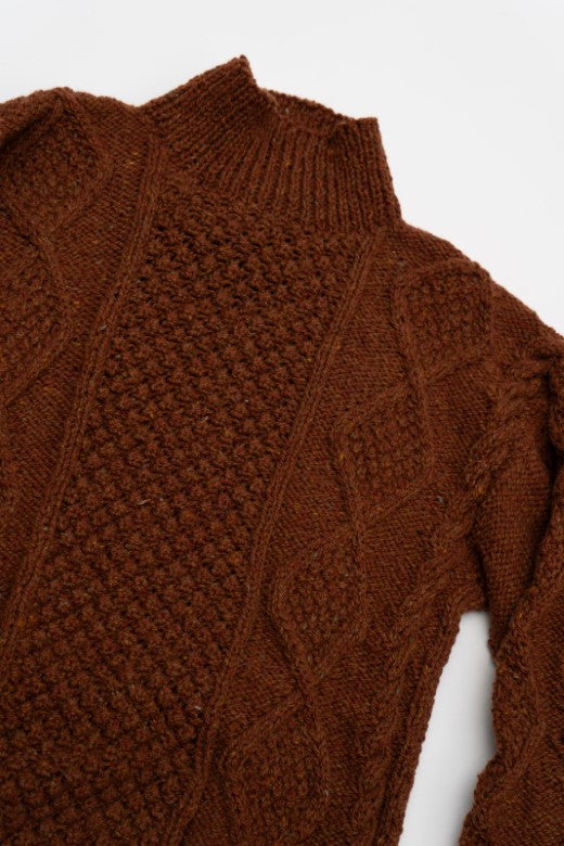 Rust-colored handknit merino wool Aran jumper featuring intricate blackberry and cable stitching by Irish craftspeople.