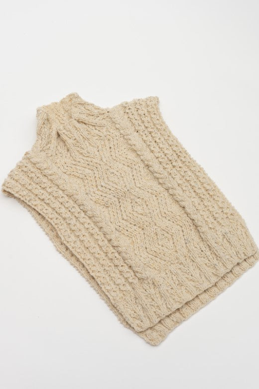Cream-colored handknit Aran cable body bib, crafted in Ireland with intricate wool textures and a cozy high-neck design.