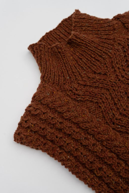 Rust-colored handknit Aran cable body bib, crafted in Donegal from high-quality wool with intricate textured stitching.