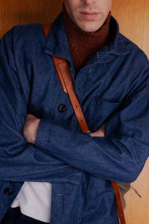 Rust-colored handknit Aran cable bib, crafted in Ireland, worn under a blue denim jacket for a layered, textured look.