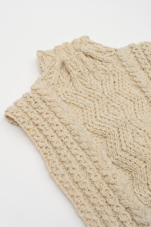 Cream-colored handknit Aran cable bib, artisan-made in Ireland with high-quality wool featuring intricate textured patterns.