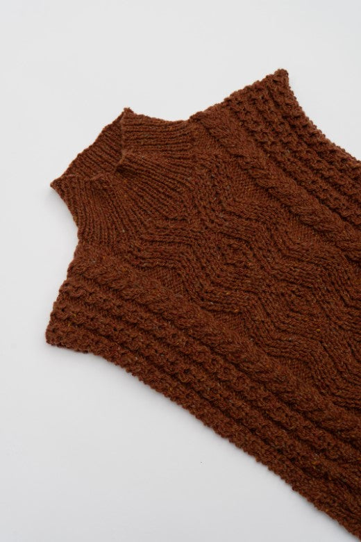 Hand-knit rust brown Aran cable body bib, crafted in Donegal from premium wool with intricate textured stitching.
