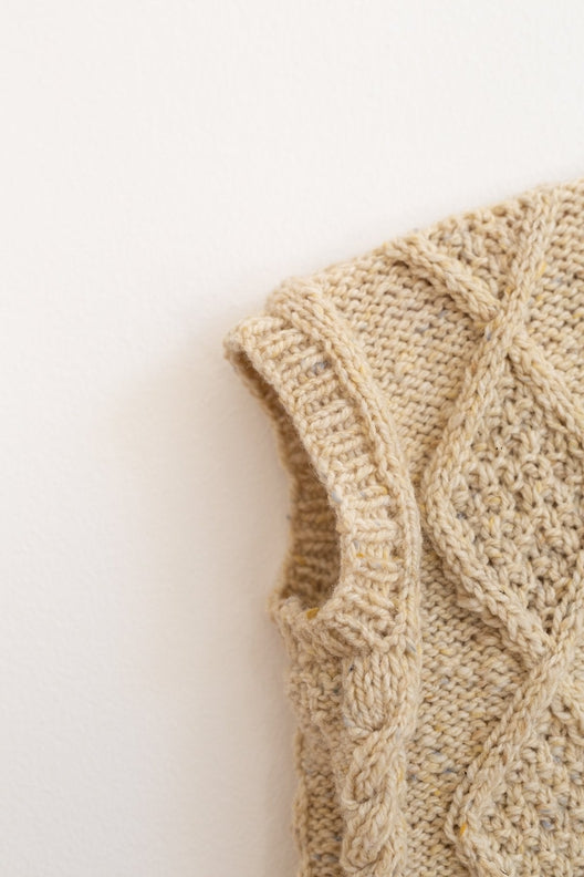 Hand-knitted Irish Aran sleeveless vest in flecked Donegal merino wool featuring traditional cable knit patterns.