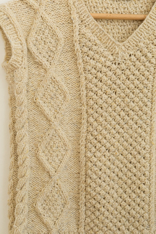 Hand-knitted Irish Aran sleeveless vest in flecked cream merino wool featuring traditional cable and diamond stitches.