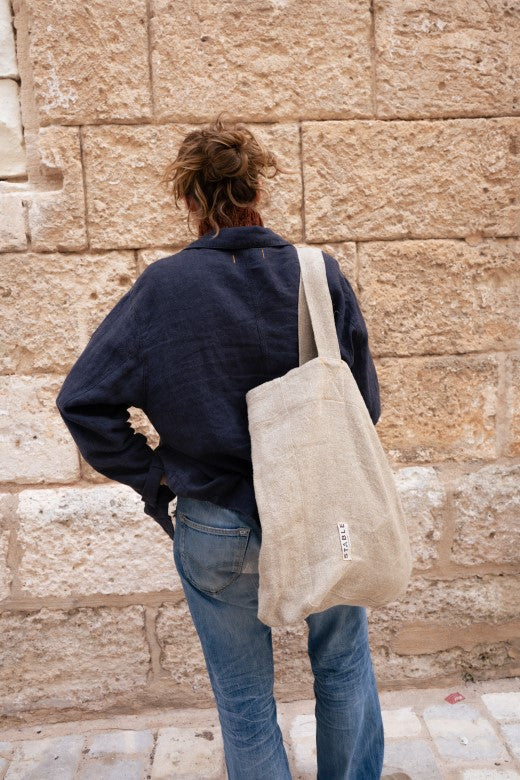 Navy blue Irish linen utility jacket with orange stitching, worn boxy with a matching Stable tote bag.