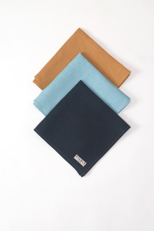 Three heavy-weight Irish linen napkins in ochre, blue, and navy, handmade in Ireland with a signature STABLE label.