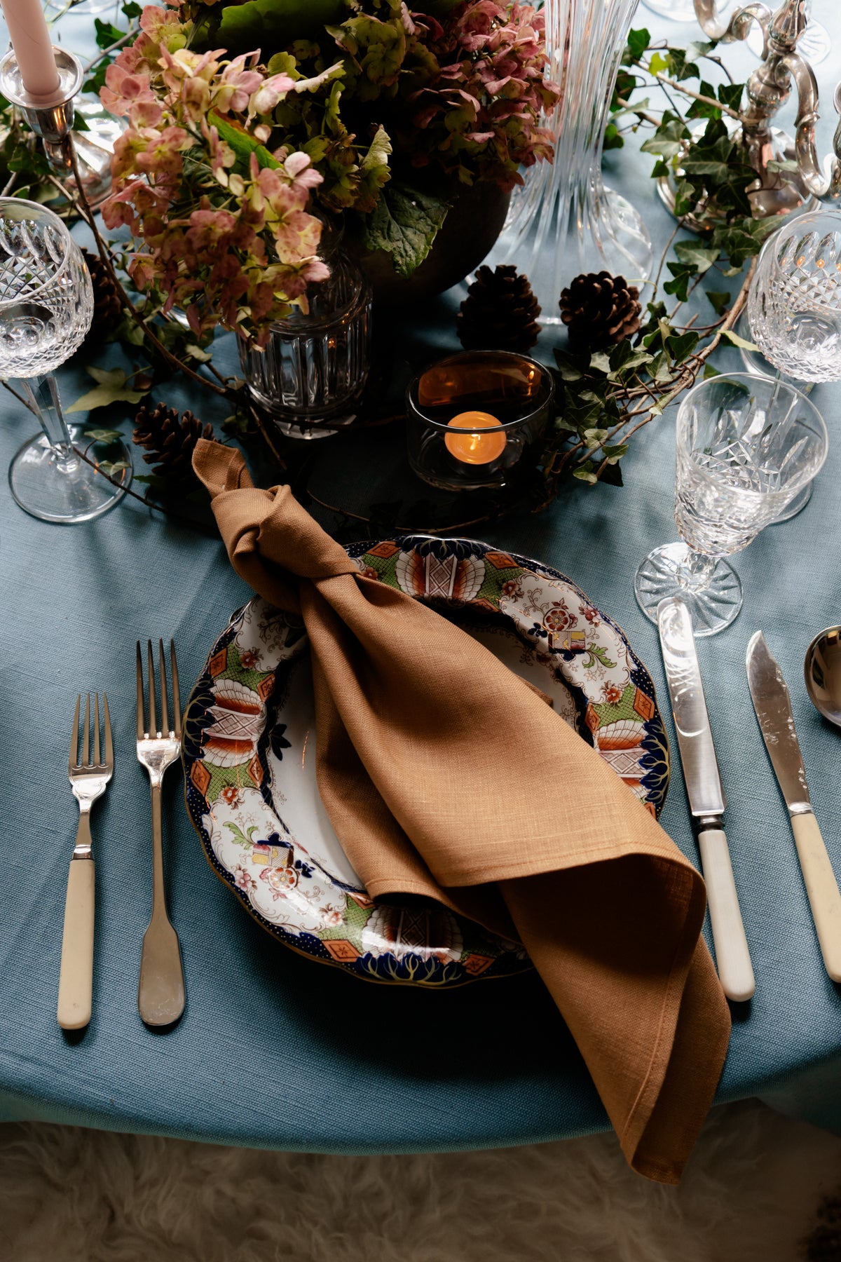 Tan heavy-weight Irish linen napkin handmade in Ireland, styled on a patterned plate with elegant table settings.