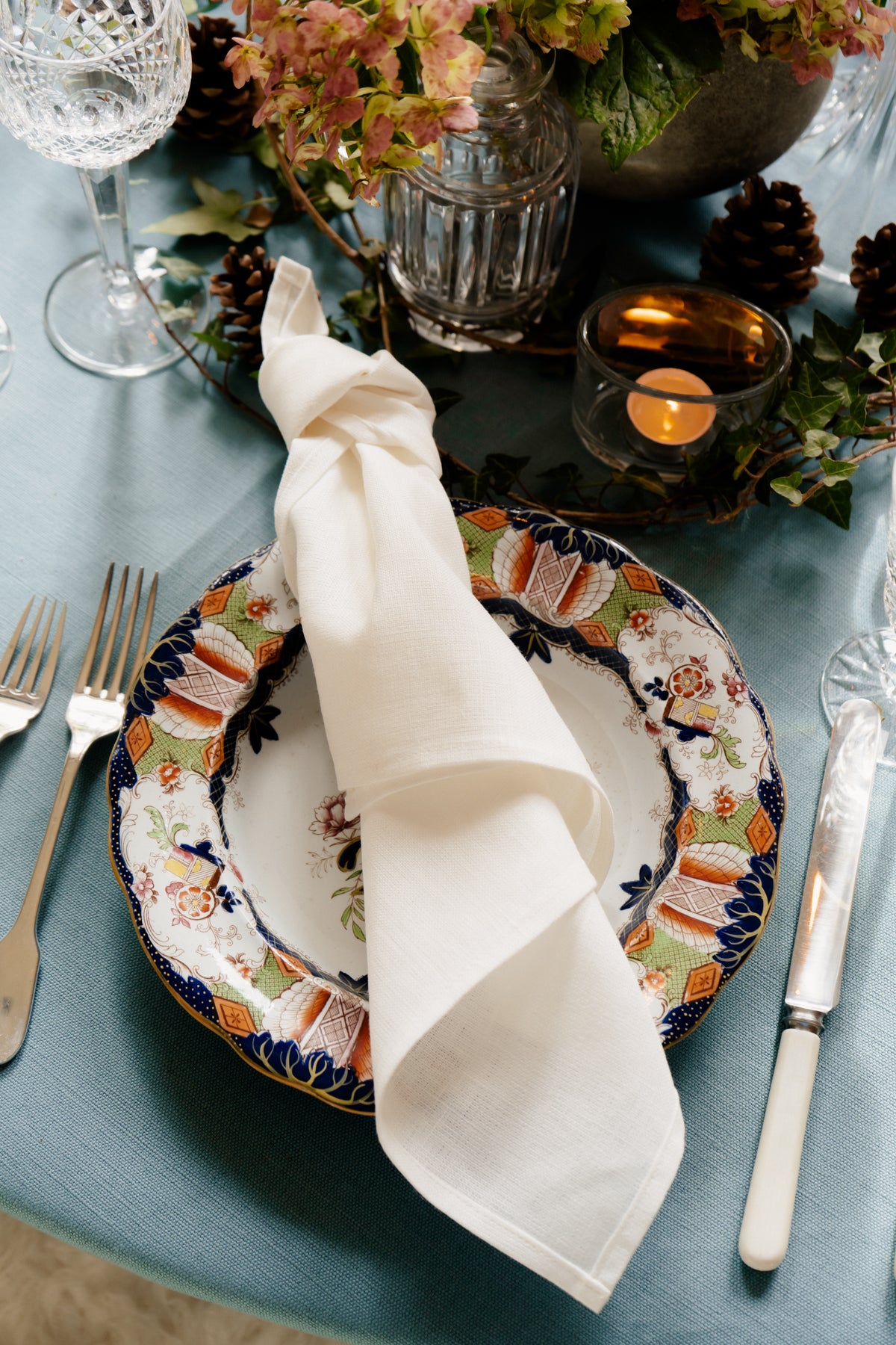 Handmade white Irish linen napkin on a patterned plate, showcasing premium heavy-weight textile craftsmanship from Ireland.