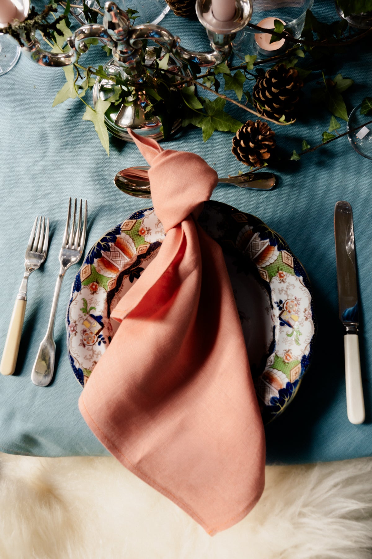 Handmade Irish linen napkin in soft peach, styled on a patterned plate by Irish makers for a high-quality table setting.
