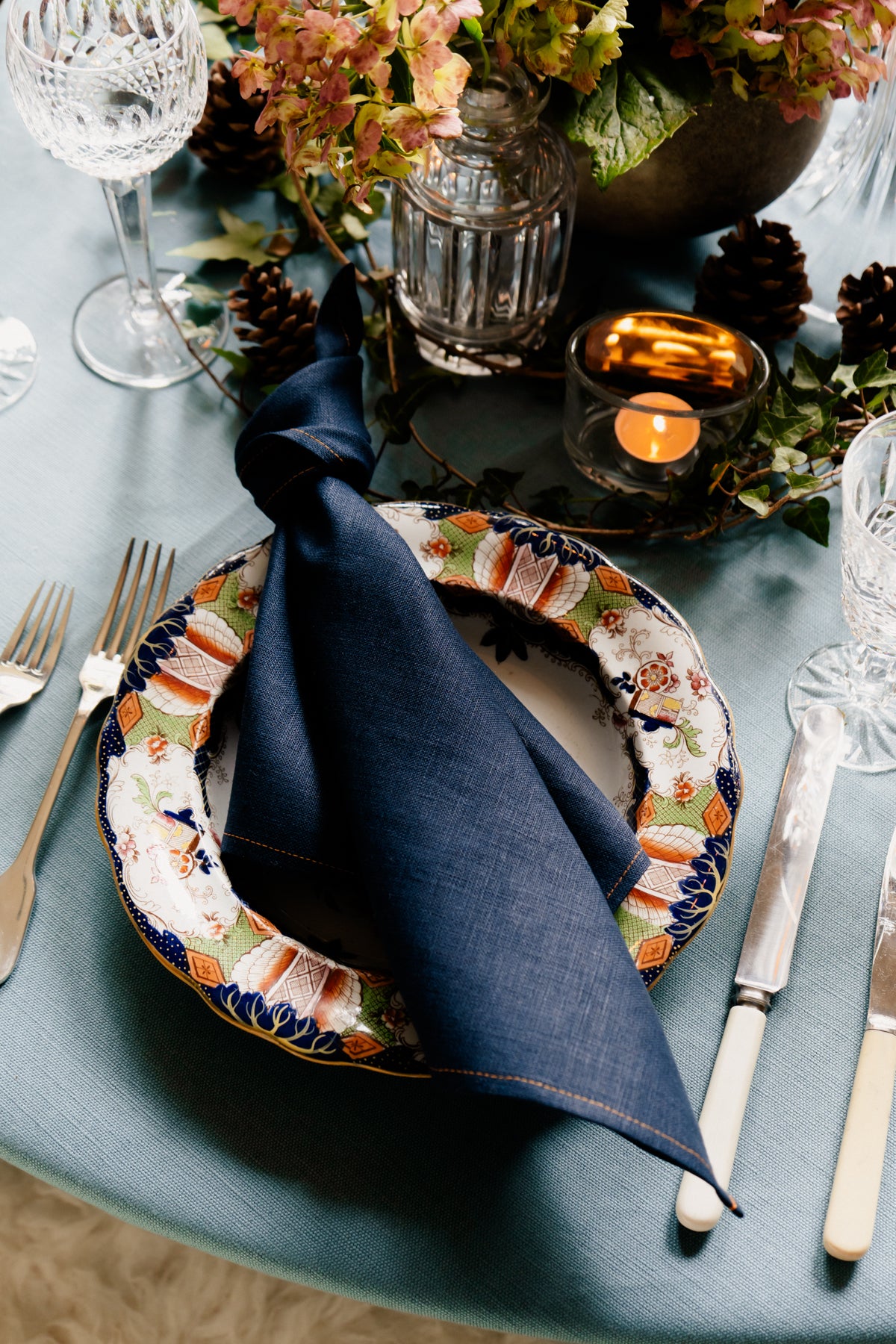 Handmade navy blue Irish linen napkin on a patterned plate, showcasing premium textile quality from Irish makers.