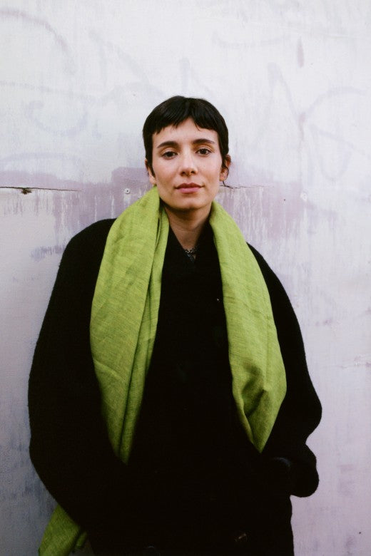 Person wearing a quince green herringbone Irish linen scarf, handcrafted by Irish makers from sustainable, high-quality flax.