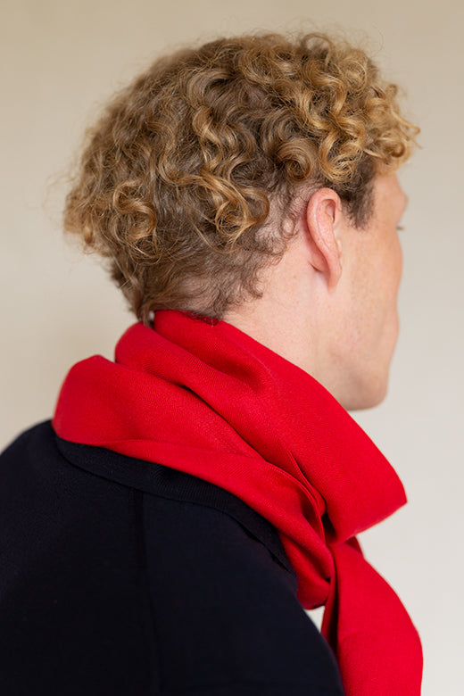 A vibrant red Irish linen scarf with frayed edges, handcrafted by Irish makers from high-quality, sustainable flax.