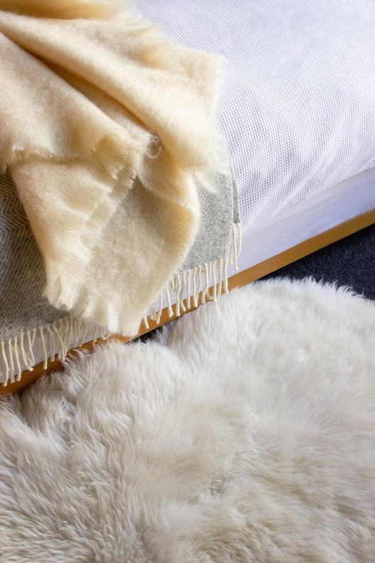 Luxurious, cream-colored Irish sheepskin rug handcrafted by local artisans, paired with a soft, high-quality wool throw.
