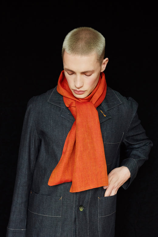 Model wearing a vibrant orange herringbone Irish linen scarf, handcrafted by Irish makers from sustainable, high-quality flax.