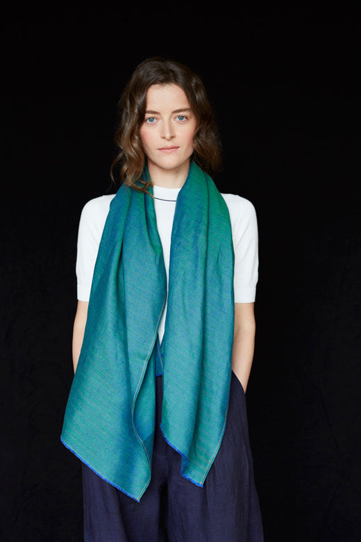 A person wearing a sea green Irish linen scarf, handcrafted by Irish makers from high-quality, sustainable flax fabric.